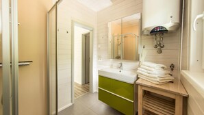 Un bagno moderno con un mobile lavabo bianco, armadietti verdi, uno specchio grande e una zona doccia.