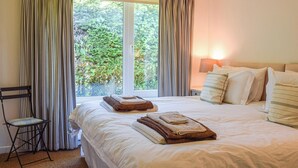 A hotel room with a large bed, two bedside tables, a chair, and a window with curtains. - 3 bedroom accommodation in Gorran Haven (Gorran Haven)