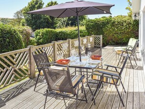Eine Terrassengruppe mit Tisch und Stühlen, beschattet durch einen Sonnenschirm.