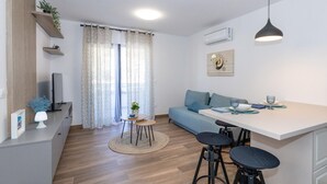 Een moderne keuken met een eethoek, voorzien van een bank, barstoelen en een kleine tafel met een plant.