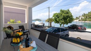 Een balkon met een eettafel, met uitzicht op een jachthaven met boten en een auto die in de buurt geparkeerd staat.