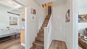 A staircase with wooden steps and white railings, leading to a door with a 'WELCOME' sign. - Midtown Flight Deck: 2BR Gem (Reno)