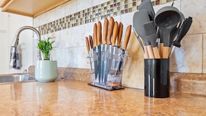 A kitchen counter with a clear knife block, a potted plant, and a utensil holder. - Midtown Flight Deck: 2BR Gem (Reno)