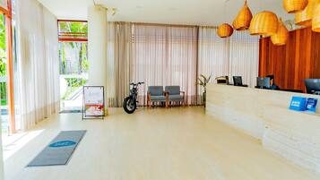 A reception area with a reception desk, two chairs, a motorcycle, and a signboard.