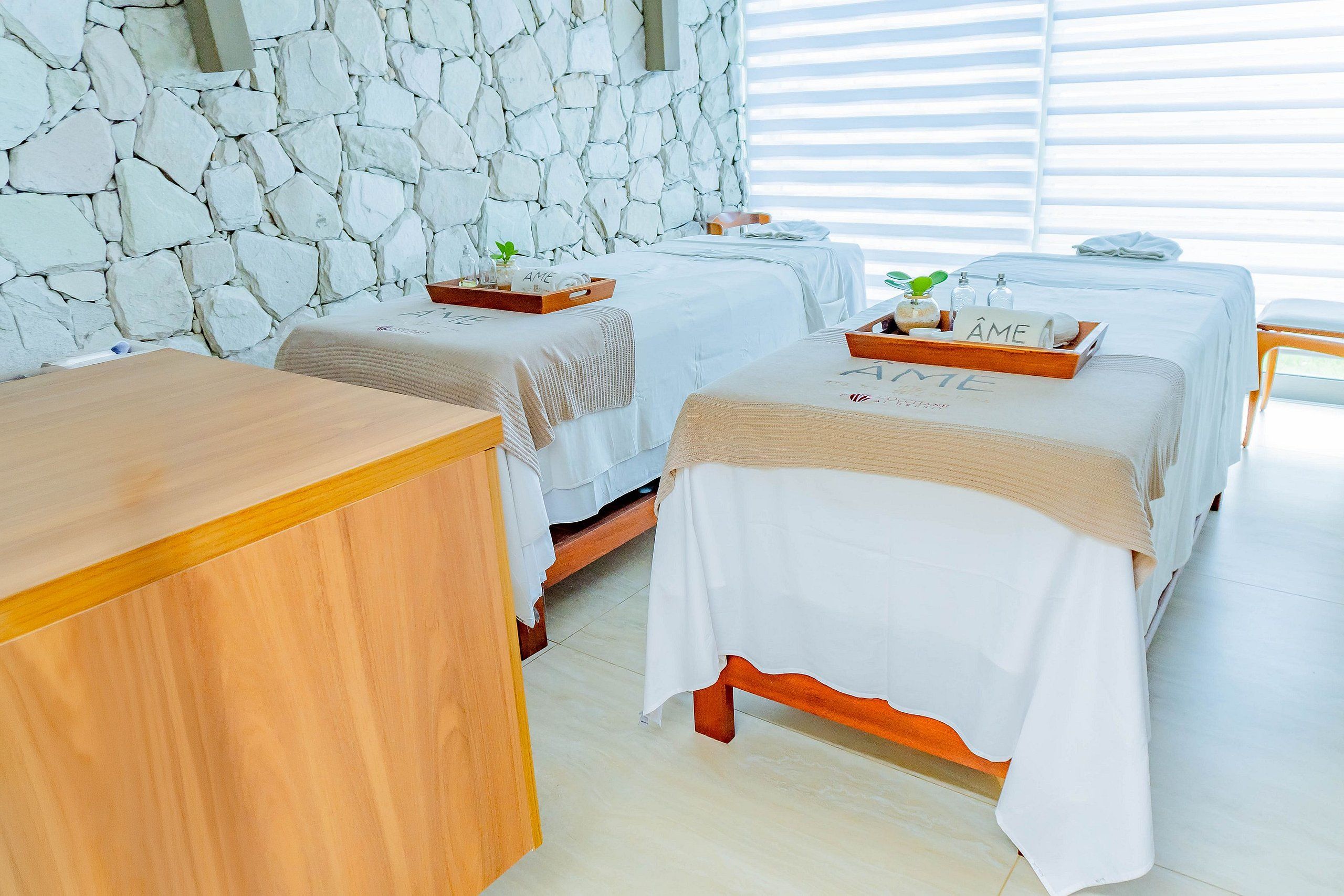 Un cuarto de spa con dos camas, un mostrador de madera y una pared de piedra.