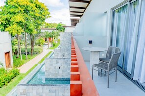 A balcony with a pool, a table with chairs, and a view of the surrounding greenery and buildings. - Ile de Pipa- Summer Pipa (Tibau do Sul)