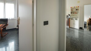 A hallway leading to a kitchen with a dining area and a window with curtains. - La casa del Cartografo (Genova)