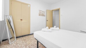 A hotel room with a bed, a wardrobe, a mirror, and a wall decoration.
