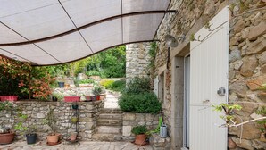 A stone building with a white door, potted plants, and a covered patio area.