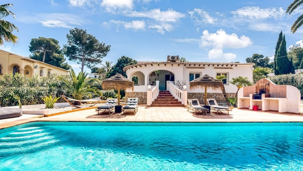 A swimming pool with lounge chairs, a staircase leading to a building, and surrounding greenery.