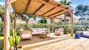 A wooden deck with outdoor furniture, a pergola, and a potted cactus.