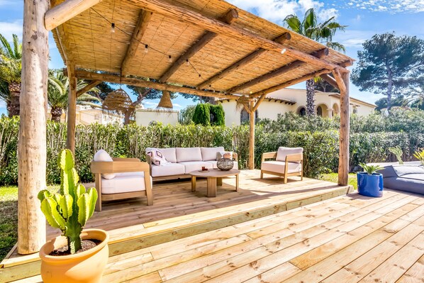 A wooden deck with outdoor furniture, a pergola, and a potted cactus.