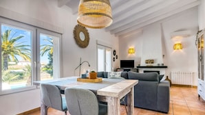 A modern living room with a sofa, dining table, and chairs, a TV, and a fireplace.