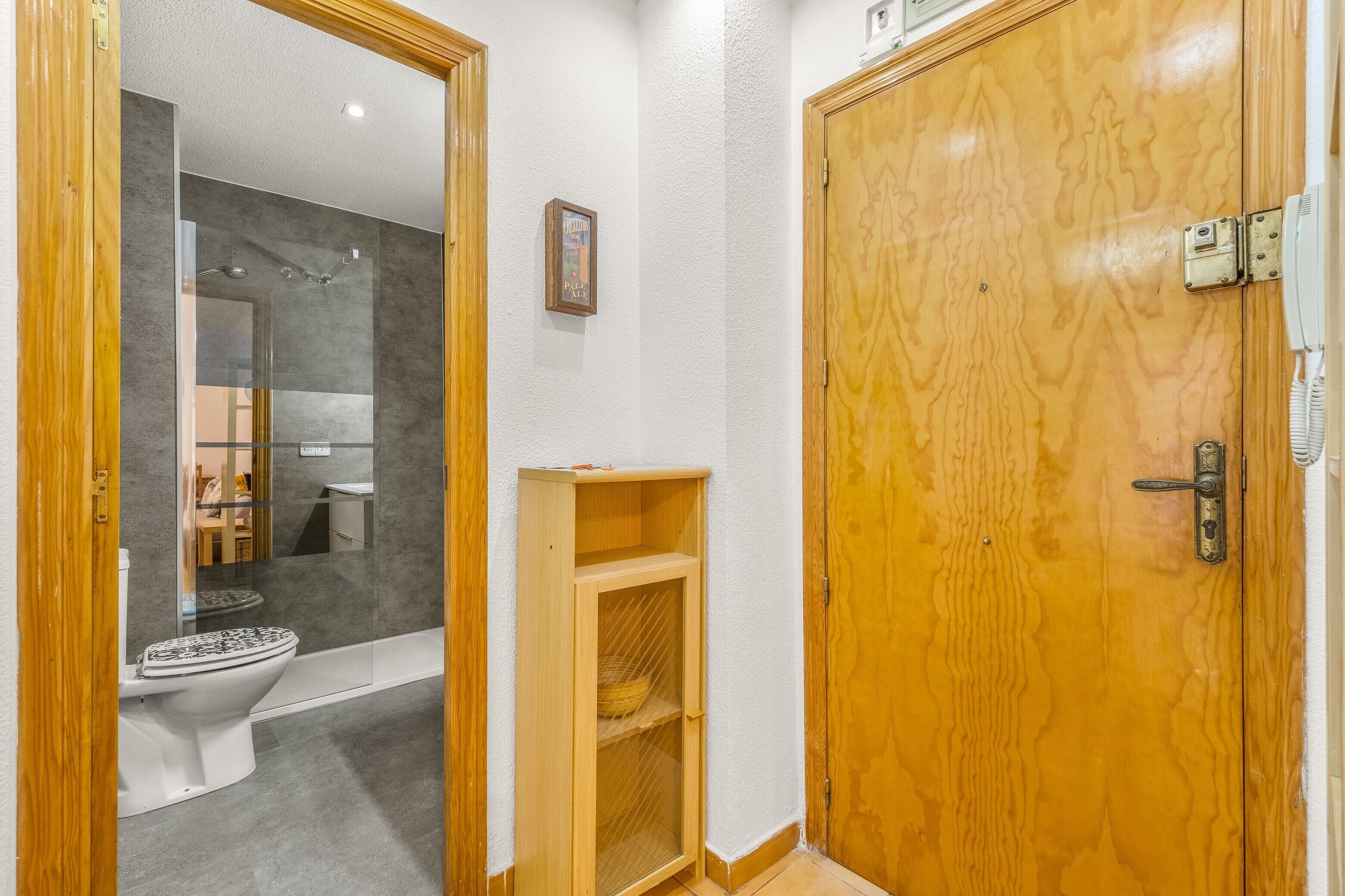 Une salle de bain équipée de toilettes, d’une douche et d’une porte en bois avec une serrure.