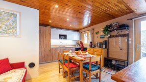 L’intérieur d’un chalet accueillant comprend un coin repas, une cuisine et un lit avec une literie rouge.