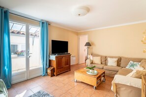 A living room with a sofa, television, wooden cabinet, and a sliding glass door. - Maison Belle Vue: Peaceful Stay with Alpilles View in Les Angles (Les Angles)