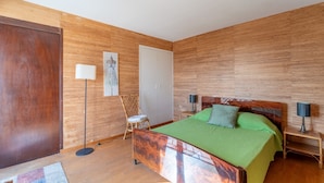Une chambre à coucher avec une tête de lit en bois, une couvre-lit verte, une chaise, une lampe sur pied et une table de chevet.