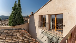 Une terrasse sur le toit offrant une vue sur le paysage environnant, une grande fenêtre et un escalier.