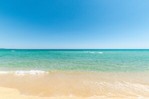 Une plage avec une eau turquoise et limpide et un rivage sablonneux.