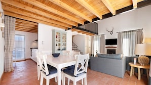 Un espace repas comprenant une table et des chaises en bois, un canapé gris et un escalier menant à un niveau supérieur.