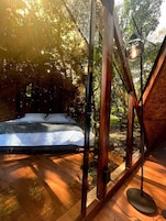 Un dormitorio con cama, suelo de madera y vistas al exterior.