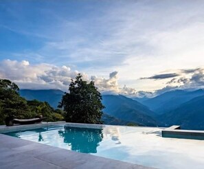 A pool with a view of mountains and a tree. - UMA experience (Coroico)