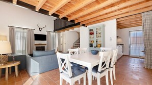 Amplia sala de estar con mesa de comedor, sofá y cocina al fondo.