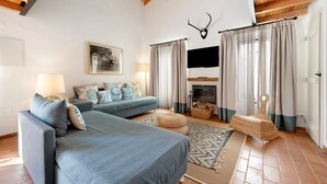 Una sala de estar acogedora con chimenea, dos sofás, un tapete y una cornamenta de venado colgada.
