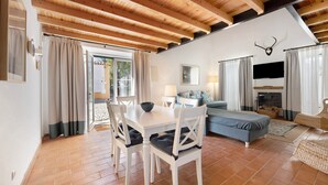 Una habitación con techo de madera, una mesa de comedor con sillas, un sofá, un televisor y una chimenea.