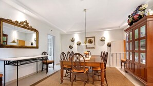 Un comedor con una mesa de madera, sillas, un espejo y un aparador.