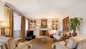 Una sala de estar con chimenea, sofás, una mesa de centro y un televisor.