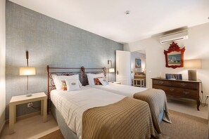 Ein Hotelzimmer mit zwei Betten, einem Nachttisch, einem Schminktisch und einer Klimaanlage.