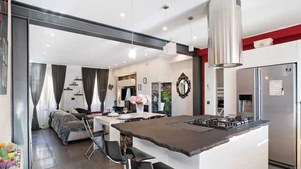 A modern kitchen with a central island, stainless steel appliances, and a dining area with a sofa and chairs.