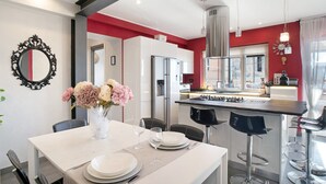 A modern kitchen with a central island, white cabinetry, and a red accent wall.