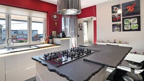 A modern kitchen with a central island, stainless steel appliances, and a red accent wall.