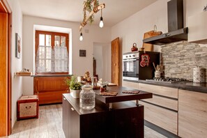 A modern kitchen with a central island, a stone backsplash, and a large window. - Casa Zito: Mountain View, Private Terrace & Wi-Fi in San Giuliano Asciano Pisa (San Giuliano Asciano Pisa)