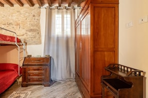 A room with a bunk bed, a wooden dresser, a cabinet, and a wooden desk.