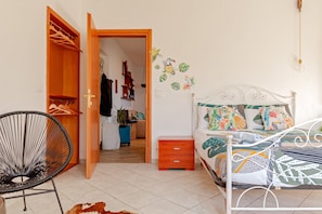 Una camera da letto con un letto, un comodino, una sedia e un armadio.