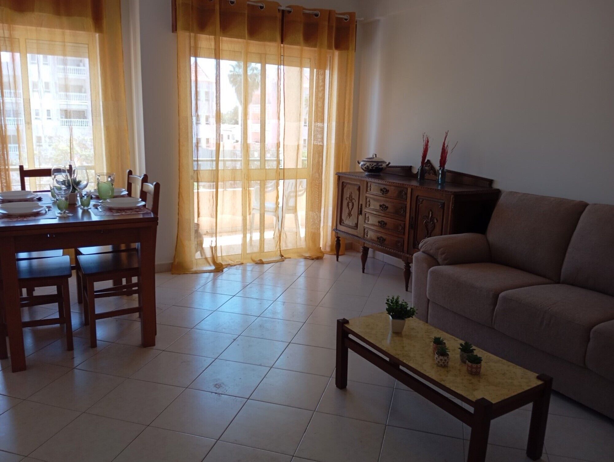 Un salon comprenant un canapé, une table basse, une table à manger avec des chaises et un buffet.