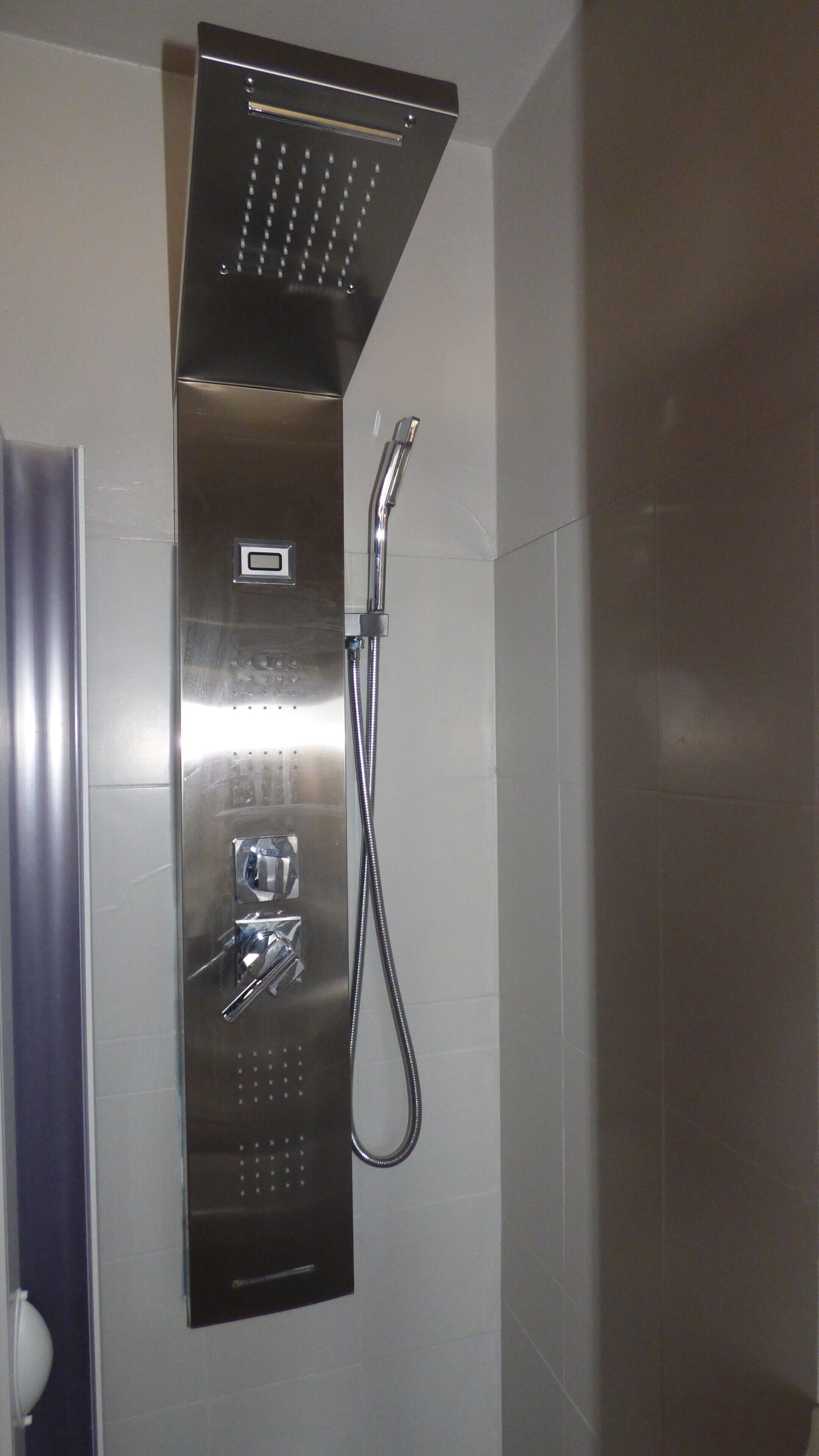 A modern shower with a control panel, a handheld showerhead, and a flexible hose.