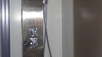 A modern shower with a control panel, a handheld showerhead, and a flexible hose.