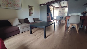 Una sala de estar con sofá, una mesa de centro y un comedor con sillas y una mesa.