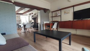 A living room with a black table, grey chairs, a sofa, and a TV on the wall. - Holiday Home 'Gnazzano Home 1' with Mountain View, Wi-Fi and Air Conditioning (Loiano)