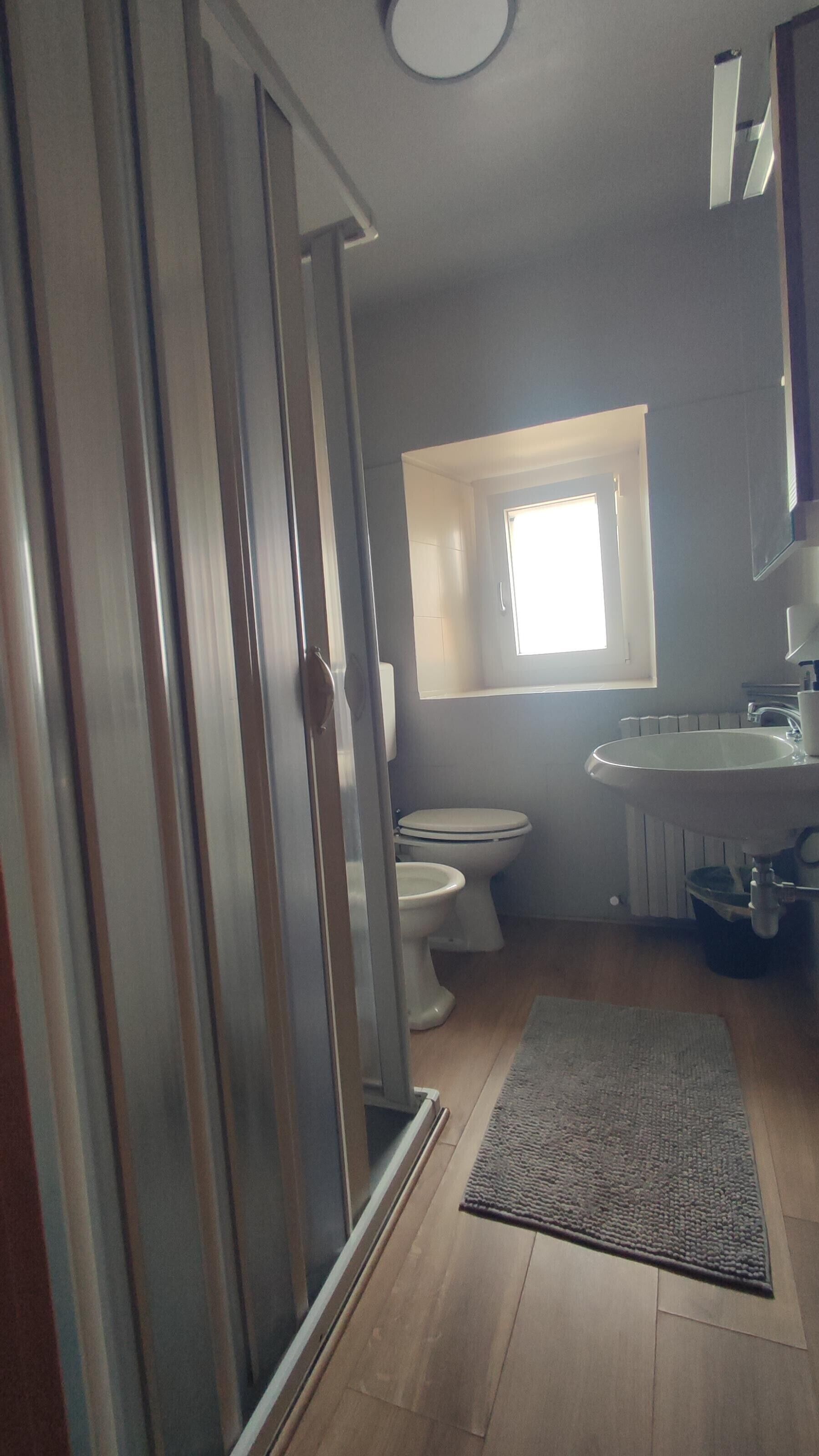 A bathroom with a toilet, sink, and a window above the toilet.