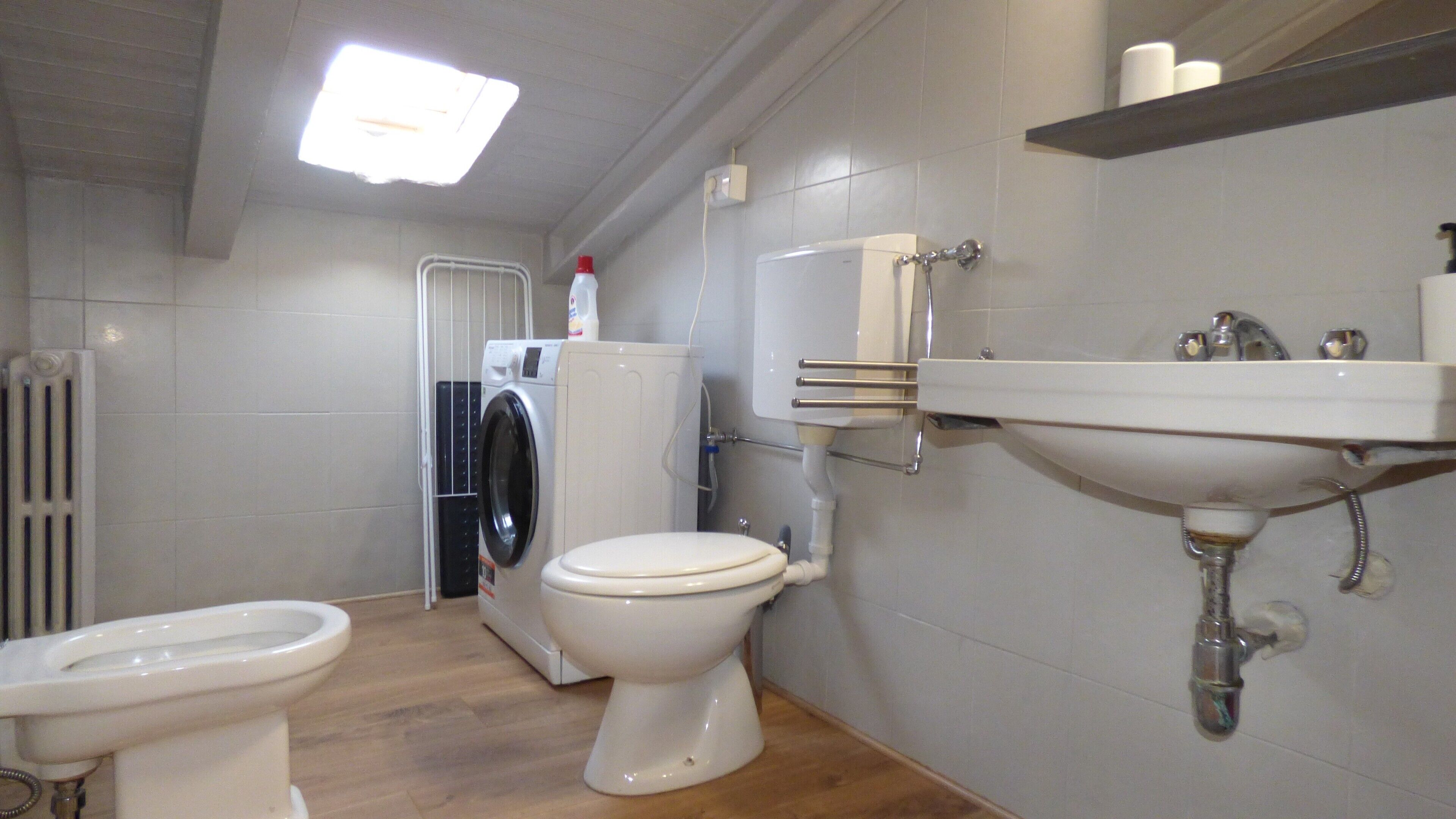 Ein Badezimmer mit Toilette, Waschmaschine, Heizkörper und Waschbecken.