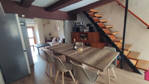 A dining area with a wooden table and chairs, a kitchen with appliances, and a staircase. - Holiday Home 'Gnazzano Home 1' with Mountain View, Wi-Fi and Air Conditioning (Loiano)