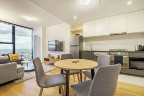 Apartamento moderno com sala de jantar, cozinha e uma grande janela com vista para a cidade.