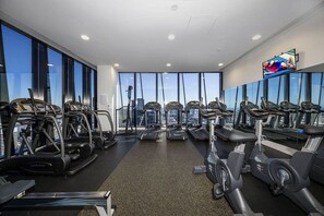 A gym with treadmills, ellipticals, and exercise bikes arranged in rows.