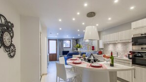 Une cuisine moderne dotée d’un îlot central, d’appareils électroménagers intégrés et d’un coin repas avec une table dressée pour deux personnes.