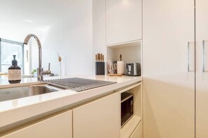 A modern kitchen with a stainless steel sink, a built-in microwave, and a sleek countertop.